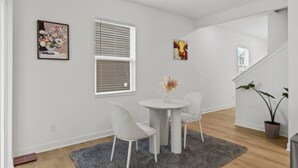 Un interior moderno con comedor, paredes blancas y una escalera.