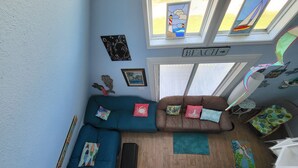 A room with a blue sofa, a brown couch, a staircase, and a 'BEACH' sign. - Fully fenced, pet friendly, 3-bedroom, 2 full bath on the beach side, sleeps 10 (Bolivar Peninsula)