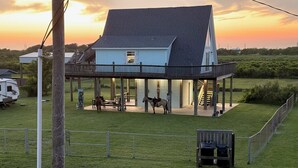 A house with a covered porch, a fenced yard, and a trailer in the background. - Fully fenced, pet friendly, 3-bedroom, 2 full bath on the beach side, sleeps 10 (Bolivar Peninsula)