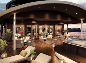 Un área de lounge exterior moderna con asientos, piscina y vistas al mar.