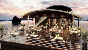 Un restaurante frente al agua con terraza, una escalera y vistas al mar.