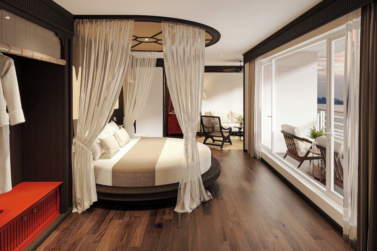Quarto com cama estofada, vista para uma varanda e piso de madeira.