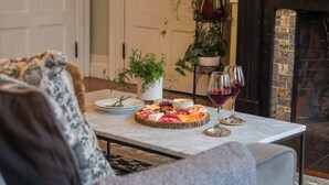 Une table à manger avec une planche de charcuterie, des verres à vin et des plantes en pot.