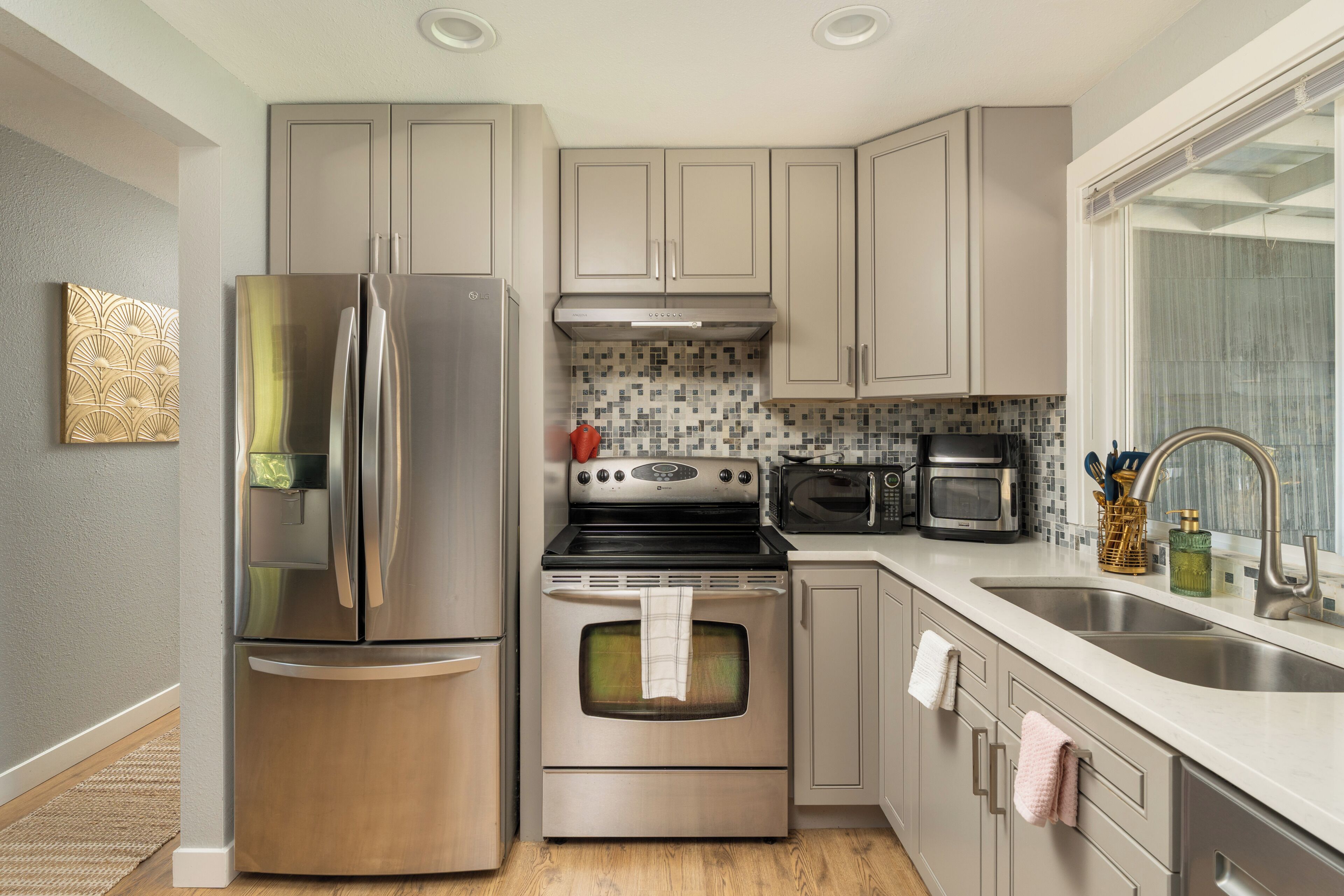 A modern kitchen with stainless steel appliances, a tiled backsplash, and a large window.