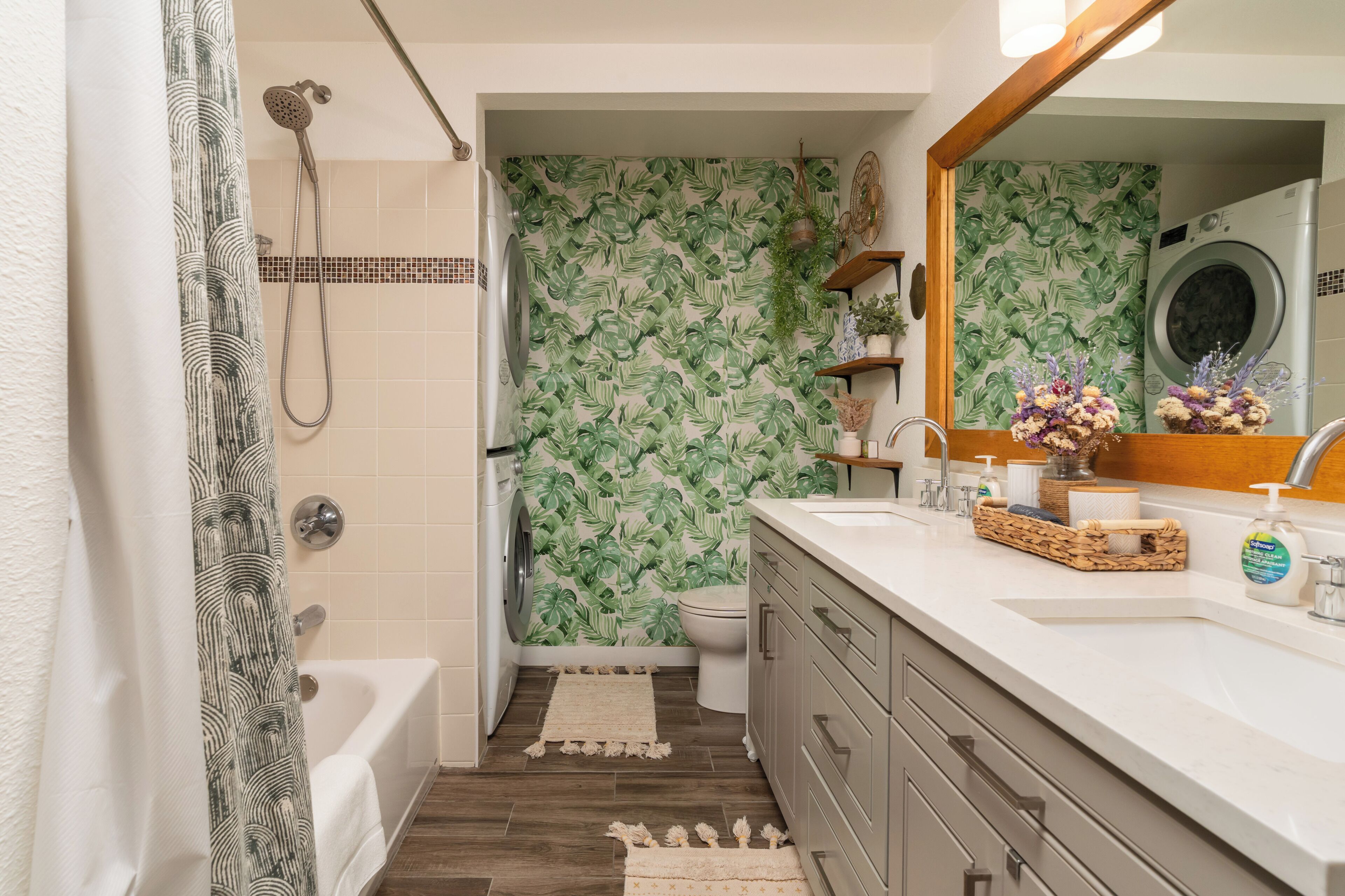 Bagno con doccia, toilette e lavandino, caratterizzato da una parete decorata con un motivo a foglia verde.