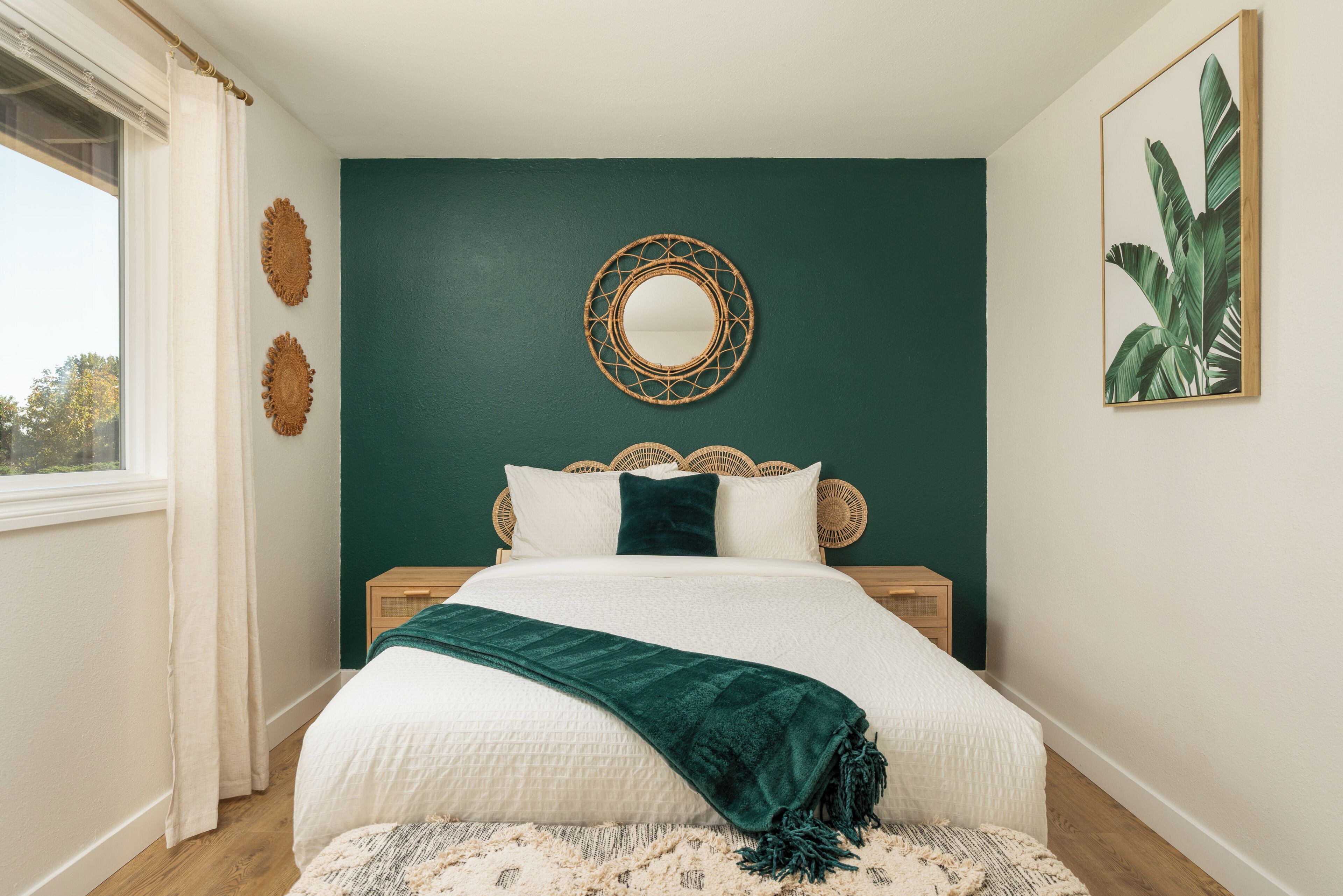 Um quarto com uma cama, um espelho redondo e uma parede com uma planta.