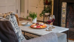 A dining table with a charcuterie board and wine glasses, surrounded by sofas and a fireplace. - Two Beautiful Apartments- Ideal for Groups! (Portland)