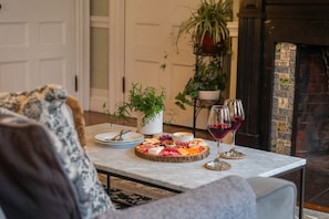 A dining table with a charcuterie board and wine glasses, surrounded by sofas and a fireplace. - Two Beautiful Apartments- Ideal for Groups! (Portland)