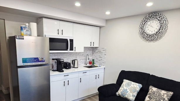 Una cocina compacta equipada con refrigerador, microondas, cafetera y hervidor.