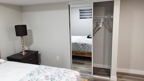 Un dormitorio con cama, mesita de noche, lámpara, armario y espejo.
