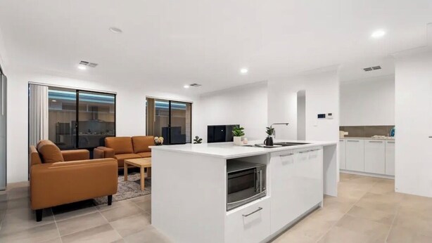 Een moderne keuken met een centraal eiland, een zithoek met een bruine bank en een groot raam.