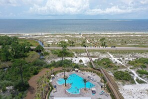 Um resort com uma piscina grande, um calçadão e vista para o oceano.