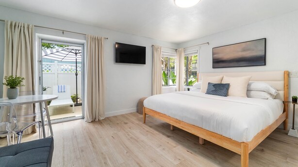 Un dormitorio con cama, televisor, ventana y vistas al exterior.