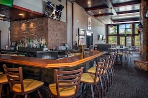 Un espace bar avec un mur en briques, des tabourets de bar et un comptoir.