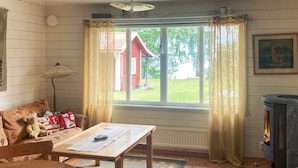 Et hyggeligt rum med et træbord, en sofa, en bamse, en pejs og et vindue med gardiner.