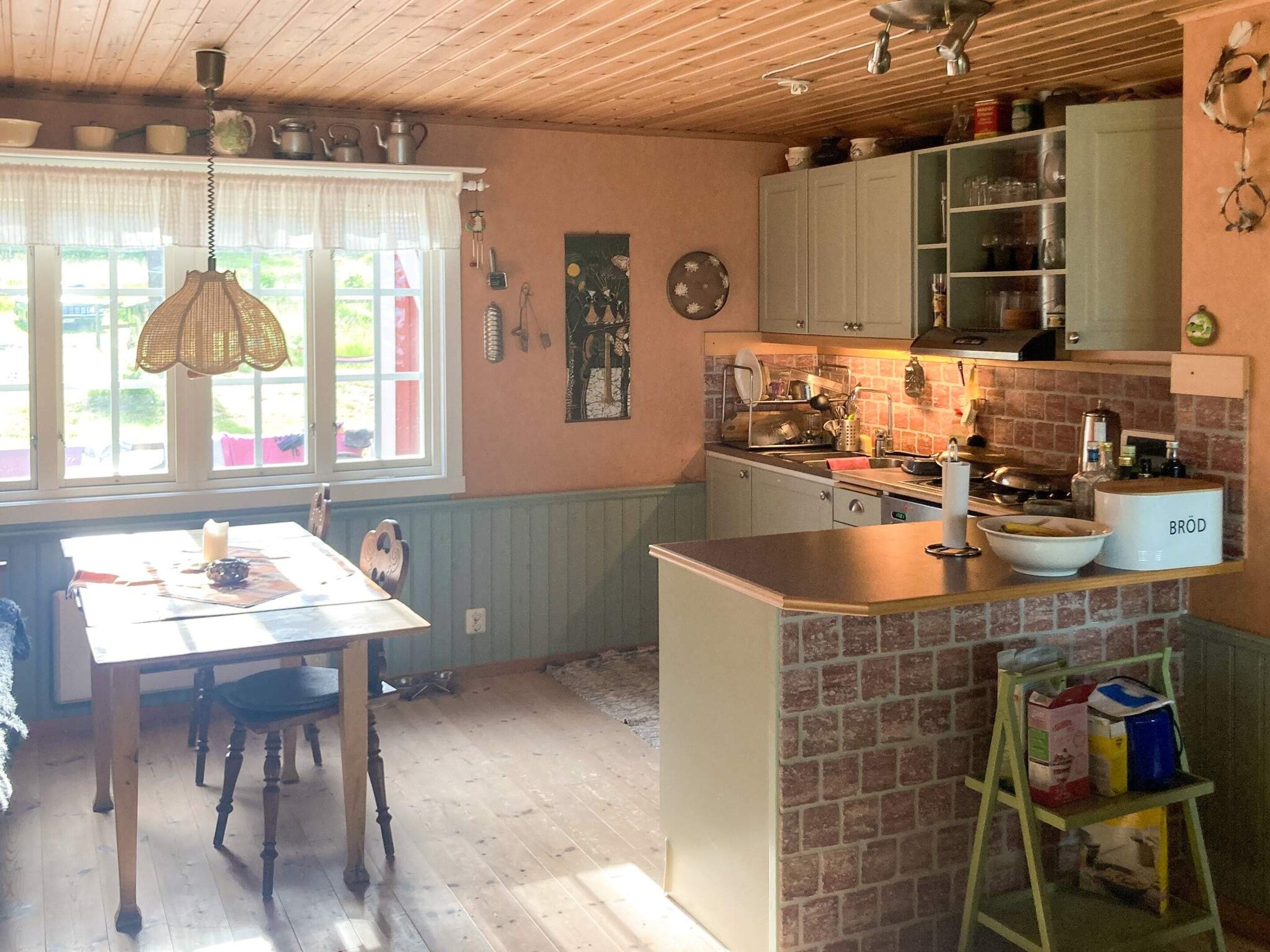 A kitchen with a dining area, wooden ceiling, and a window with a view.