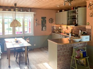 A kitchen with a dining area, wooden ceiling, and a window with a view. - 8 Person Holiday Home in Brandtorp (Brandstorp)