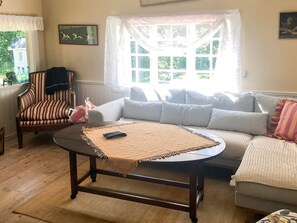 A living room with a wooden coffee table, striped armchair, and a sofa with multiple cushions. - 8 Person Holiday Home in Brandtorp (Brandstorp)