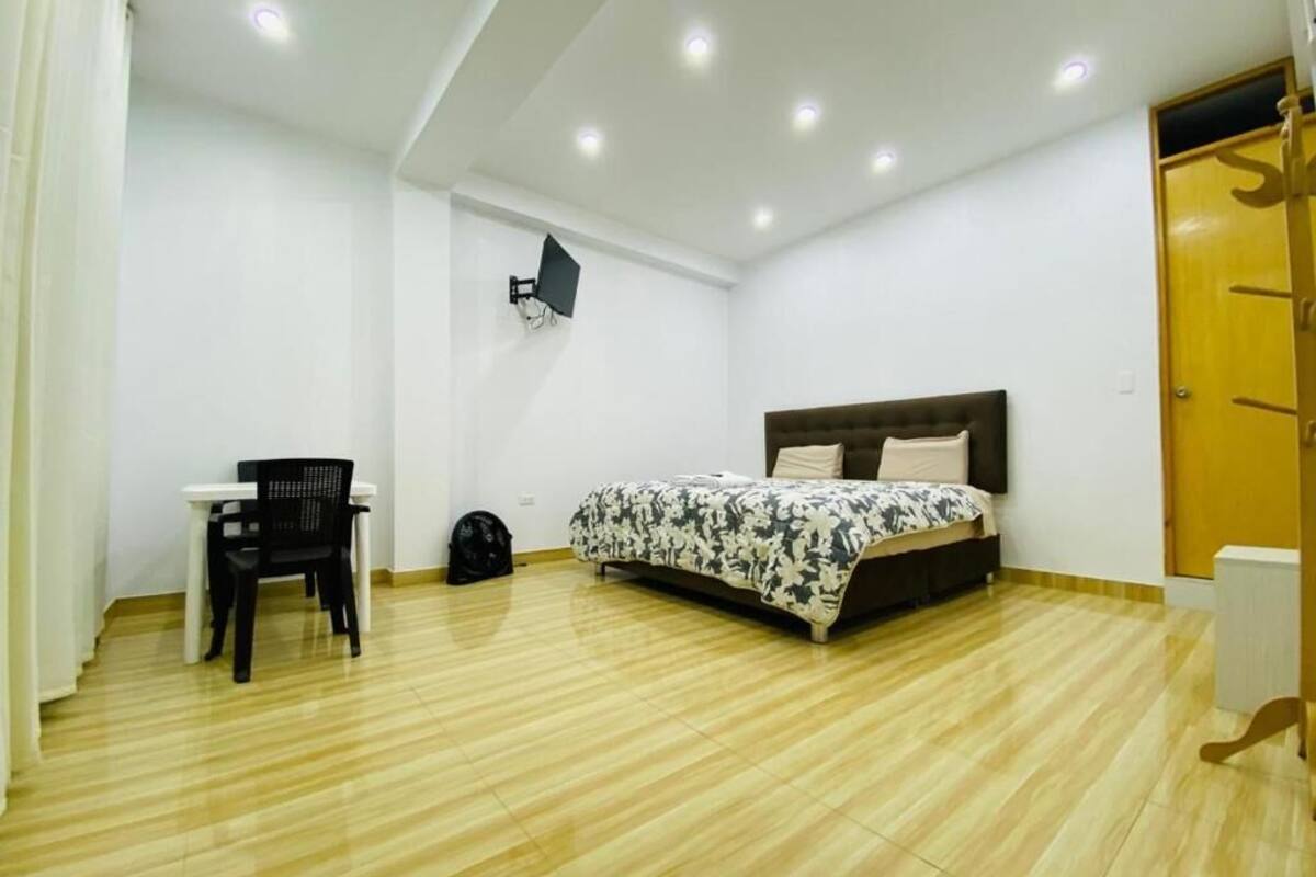 Un dormitorio con cama, escritorio, silla, televisor y armario.