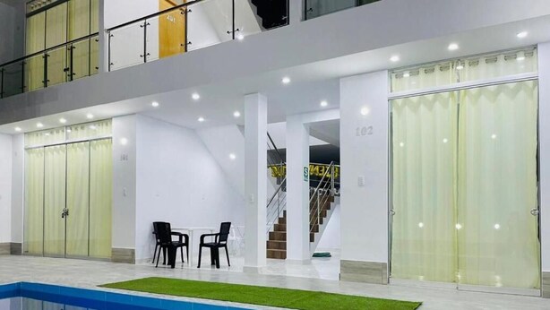 Un área interior de piscina moderna con vista despejada a la piscina, una escalera y un espacio de descanso.