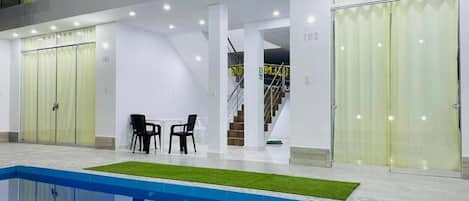 Un área interior de piscina moderna con vista despejada a la piscina, una escalera y un espacio de descanso.