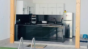 Una cocina moderna con encimera negra, electrodomésticos de acero inoxidable y armarios blancos.