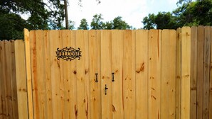 Une clôture en bois avec une pancarte indiquant « BIENVENUE » et deux portails en métal.