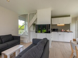 A modern living room with a grey sofa, a white coffee table, and a TV mounted on a white wall. - TuinParel by Interhome (Renesse)