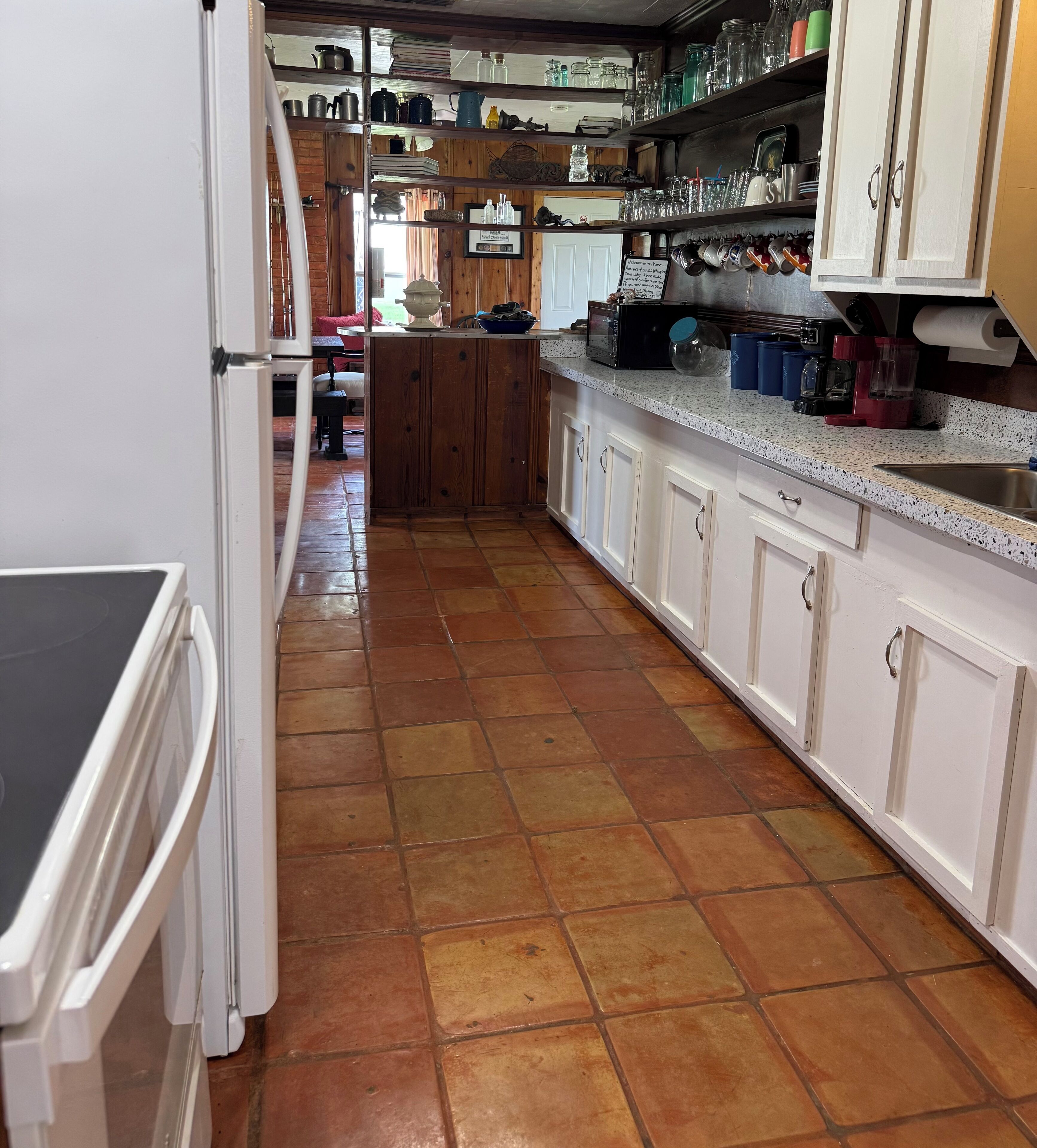 A kitchen with a tiled floor, white cabinets, and various kitchen appliances.