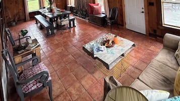 Ein gemütliches Wohnzimmer mit Holzboden, einer Couch, einem Couchtisch und einem Essbereich mit einer Bank und Stühlen.