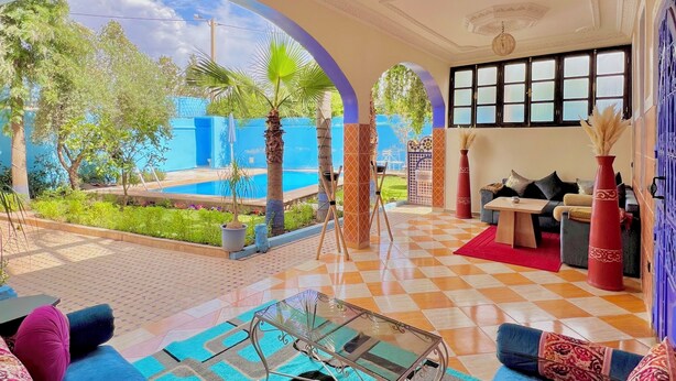 A spacious living area with a checkered floor, a glass coffee table, and a sofa with patterned cushions.