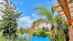 A swimming pool surrounded by lush greenery and a clear blue sky.
