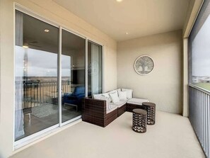 Ein Balkon mit einer Sitzecke, zwei Beistelltischen und einer Glastür zu einem Außenbereich.