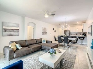 Ein modernes Wohnzimmer mit einer Eckcouch, Essbereich und Küche.