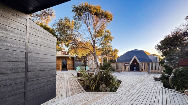 A wooden deck with a gazebo, a tent, and a building with a sign.