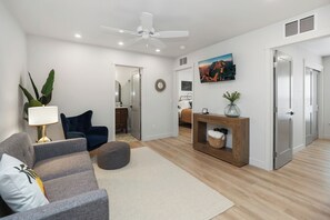 Ein modernes Wohnzimmer mit Sofa, Couchtisch, Lampe, Deckenventilator und einem Bild an der Wand.