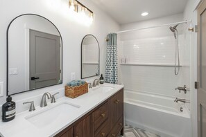 A bathroom with two sinks, a mirror, a shower, and a bathtub.