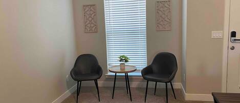A room with two chairs, a small table, and a window with blinds.