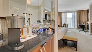 A hotel room with a kitchenette, a bed, a desk, and a view of the city. - Remodeled MGM Signature Suite High FLR  (Las Vegas)