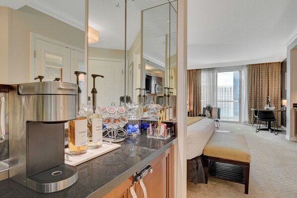 Quarto de hotel com cozinha compacta, cama, escrivaninha e vista para a cidade.