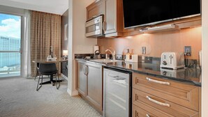 Een moderne hotelkeuken met een groot flatscreen-televisie, roestvrijstalen apparatuur en een eethoek met uitzicht over de stad.