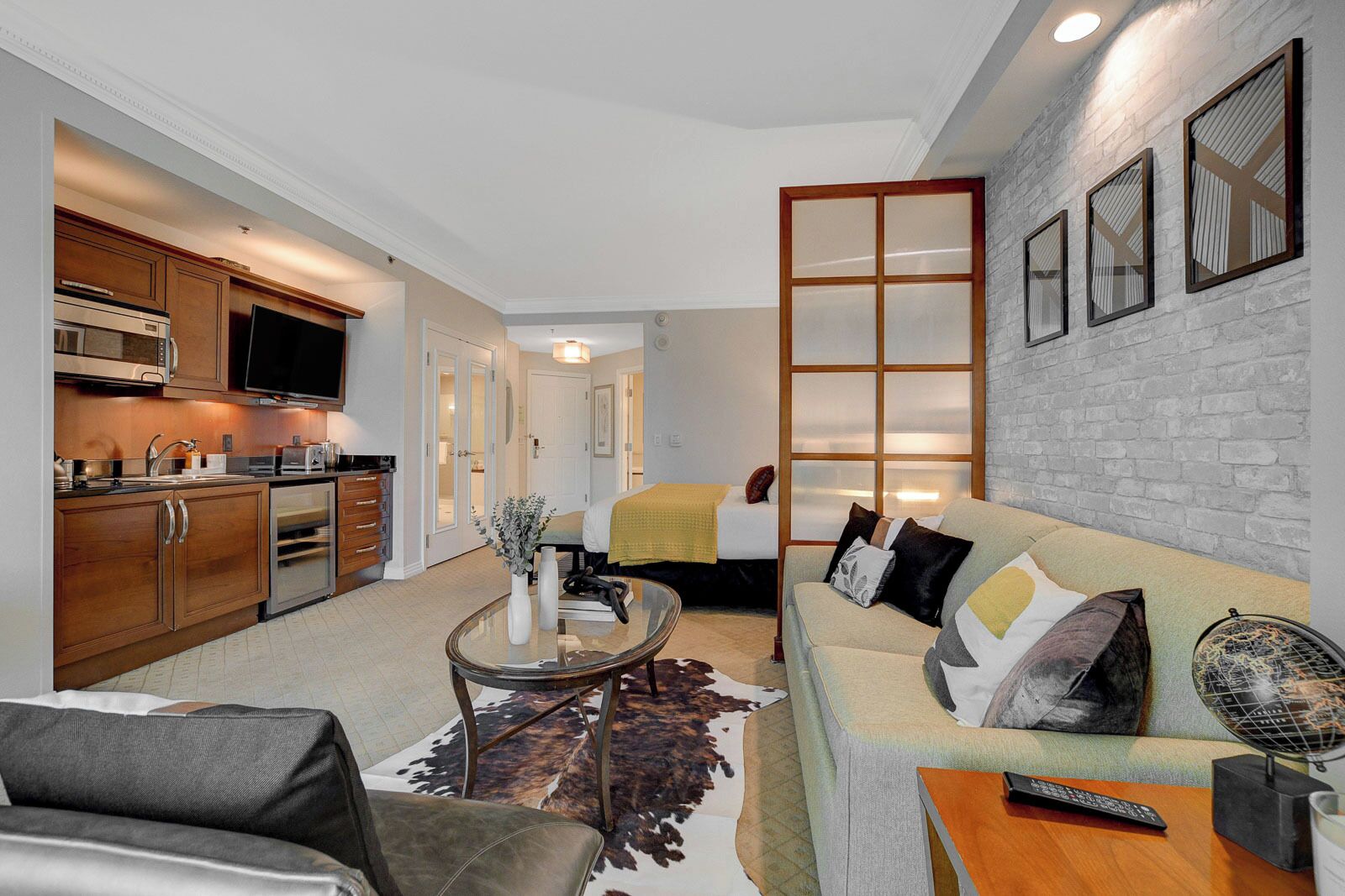 A compact living space with a kitchenette, a sofa set, a dining table, and a large mirror.