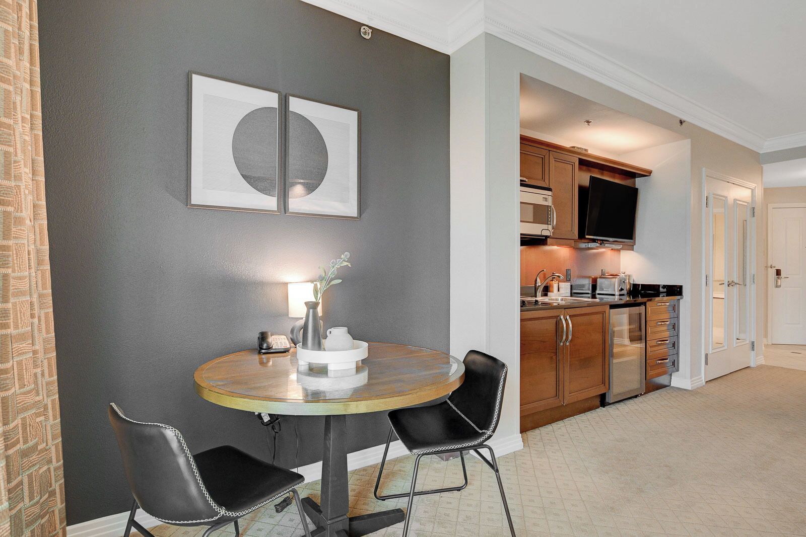 A compact kitchen with modern appliances and a dining area with a round table and two chairs.