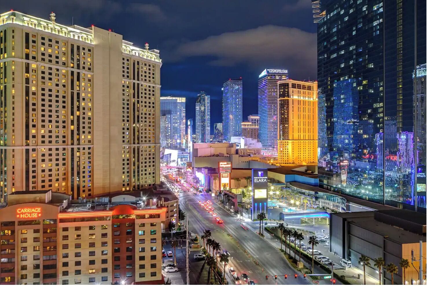 A cityscape with illuminated buildings, including a hotel named 'Carriage House' and 'Elara'.
