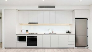 Una cucina moderna con mobili bianchi, un frigorifero in acciaio inossidabile, forno integrato e microonde.