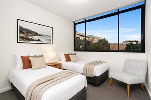 A hotel room with two beds, a chair, a large window with a view, and a framed picture on the wall. - ROSE9 - Sunlit Rosebery Stay | Balcony & Easy Airport Access (Sydney)