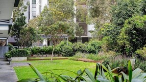 Un cortile con un prato curato, diverse piante e un edificio sullo sfondo.