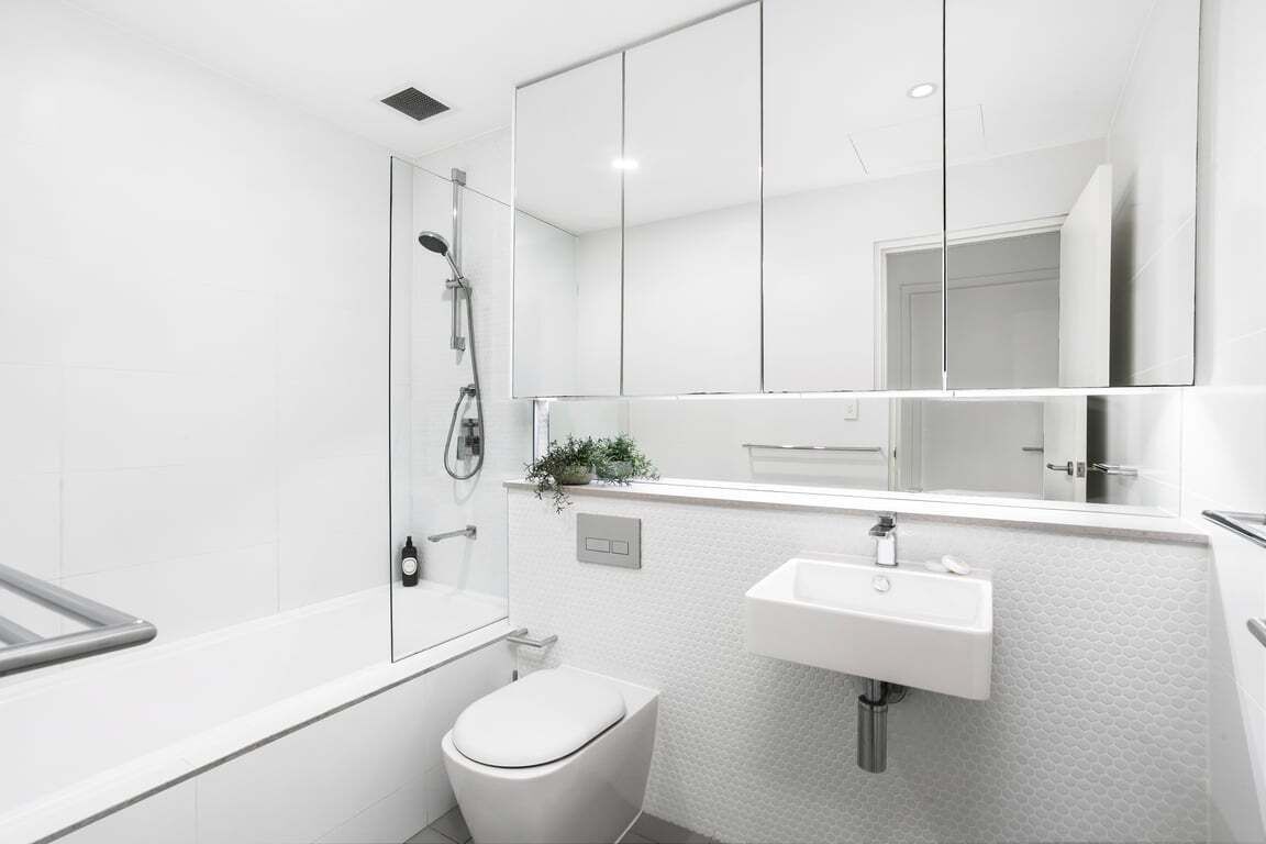 Un baño moderno con bañera, inodoro, lavamanos y un espejo grande.