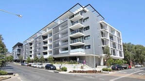 Un edificio moderno a più piani con balconi, un'area di parcheggio e cielo sereno.