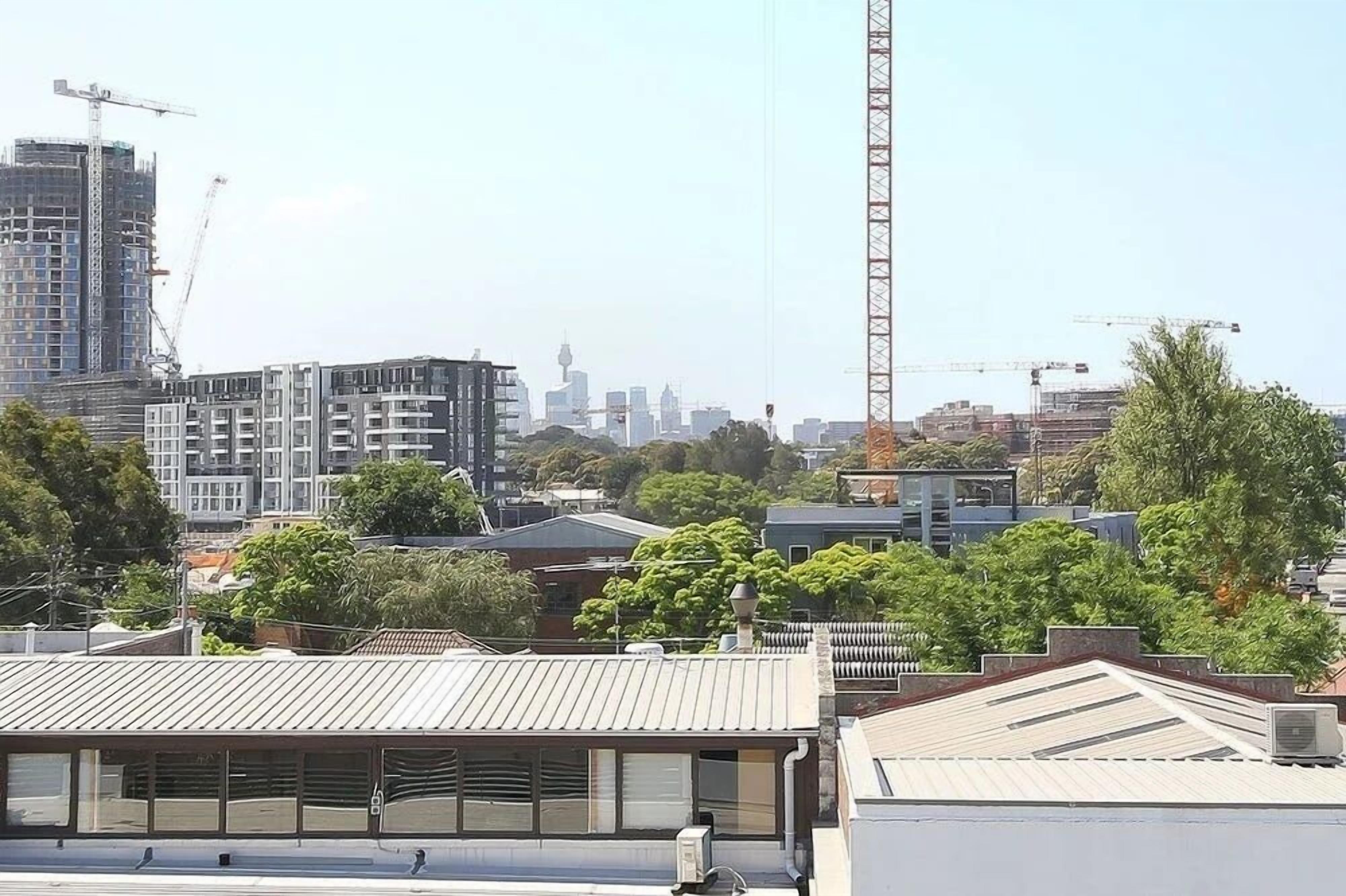 Une vue urbaine avec des grues de construction, des bâtiments modernes et un ciel dégagé.
